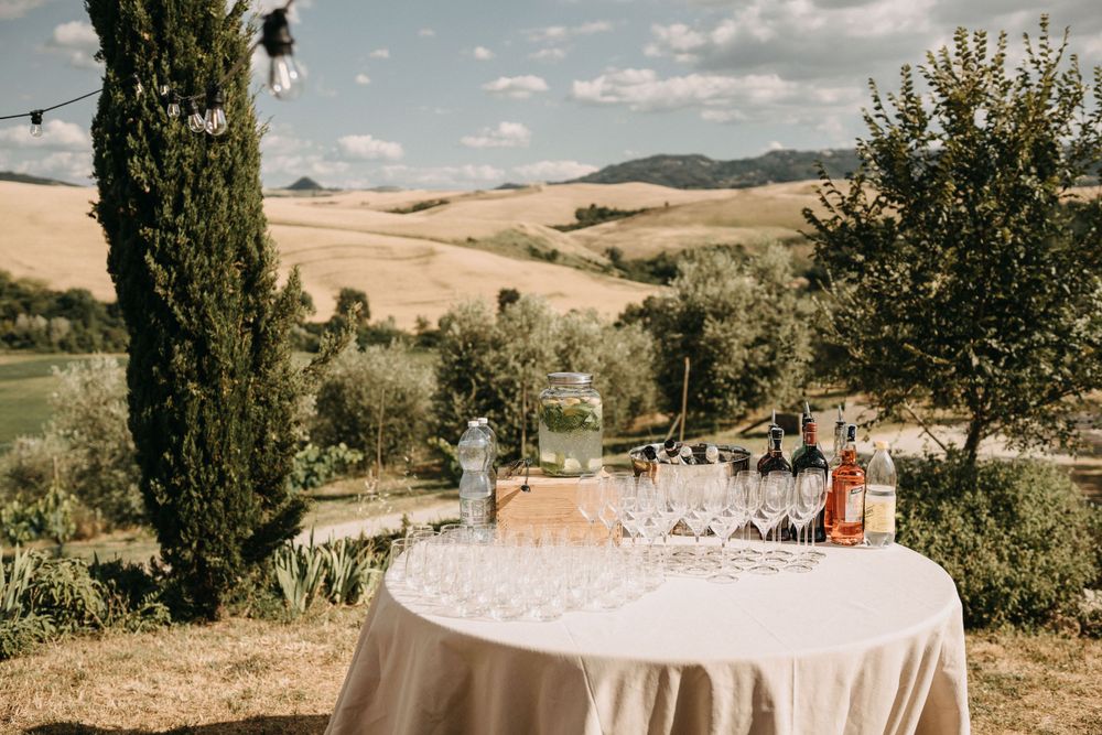 Elegant outdoor wedding reception setup with white tables against Tuscan countryside landscape.