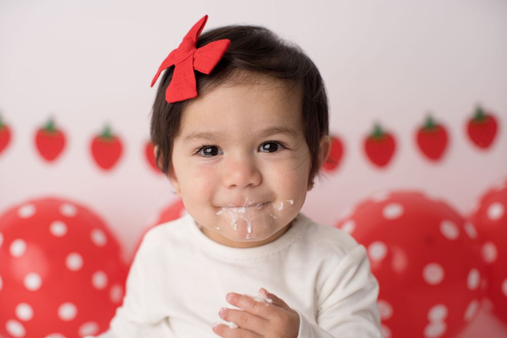 Close up portrait with red bow against strawberry themed party backdrop.