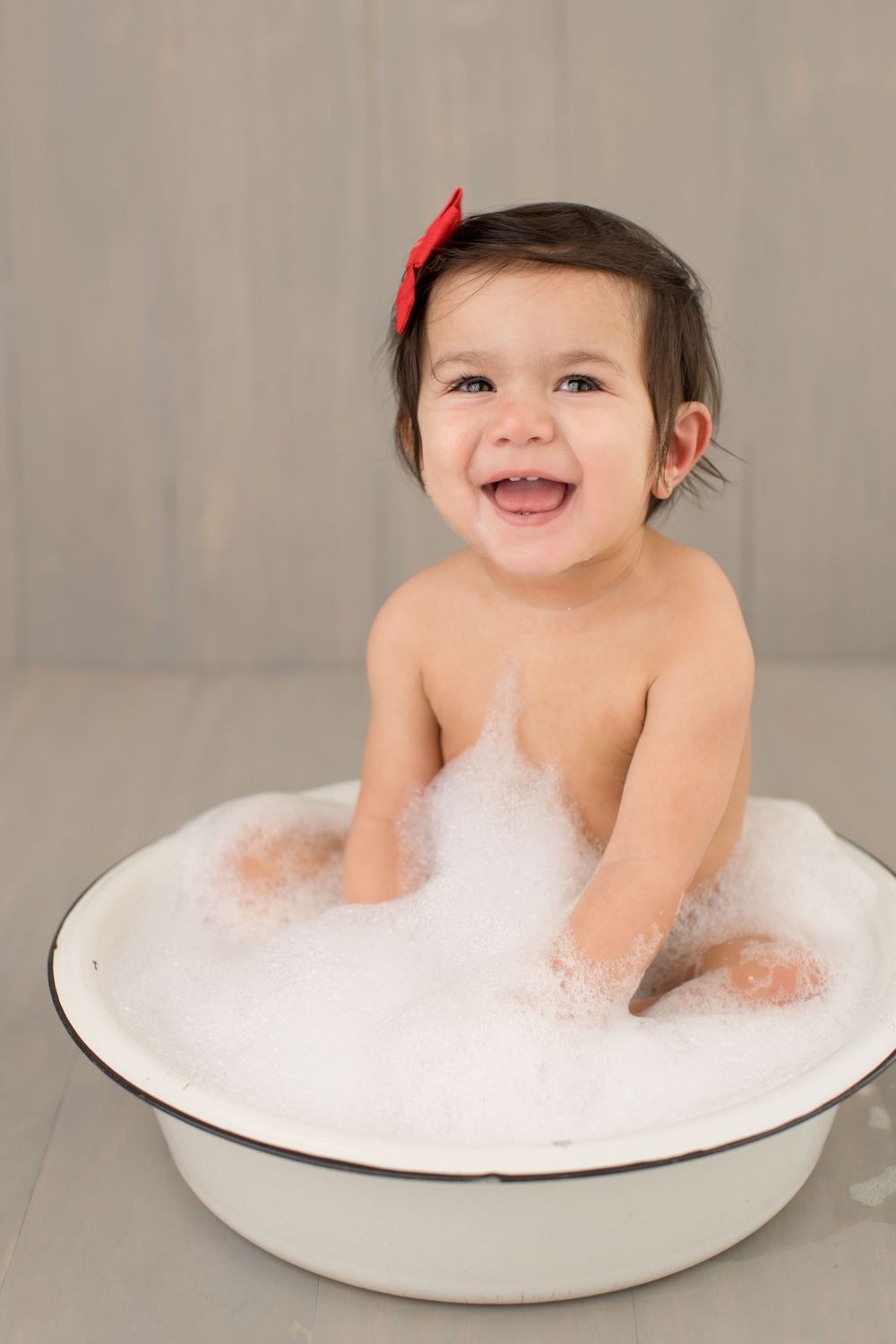 Happy bath time portrait in vintage white enamel tub with bubbles.