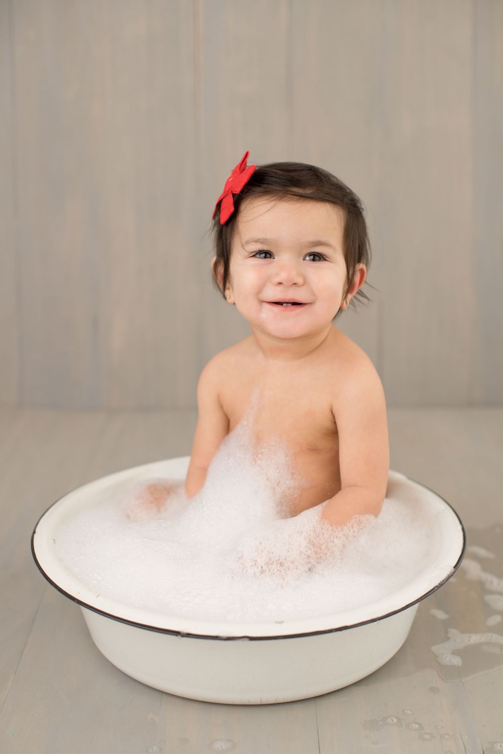 Joyful bathtime moment in white enamel tub with soap bubbles.