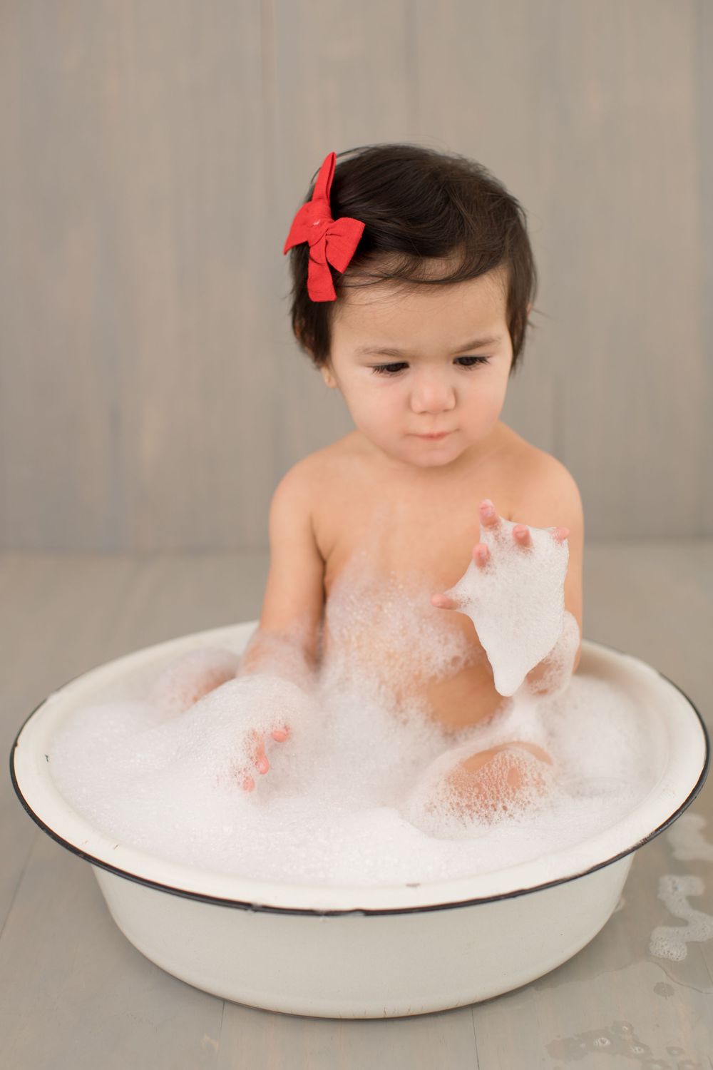 Bath time portrait in vintage enamel tub playing with soap bubbles.