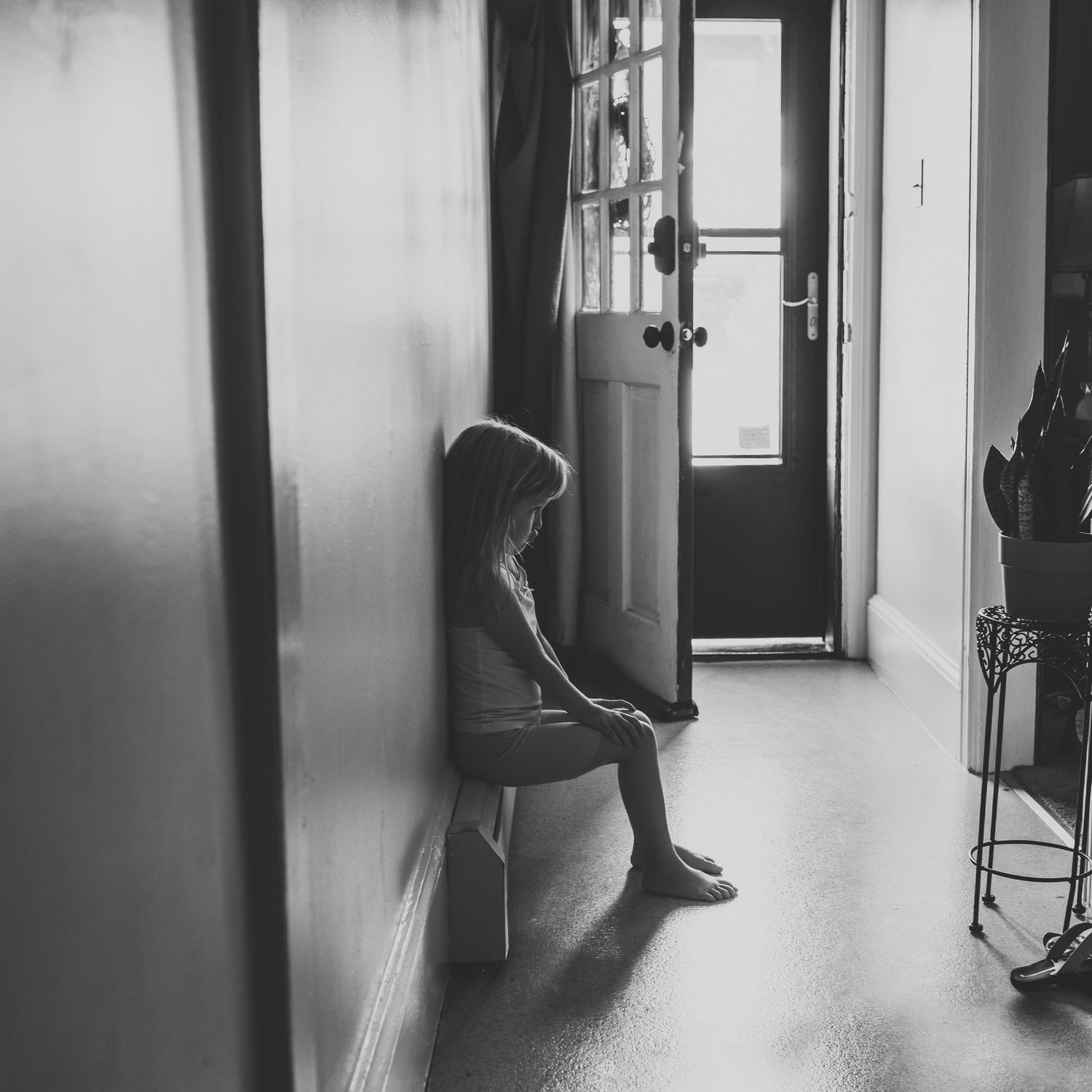 Little lonely girl sits upset in a doorway