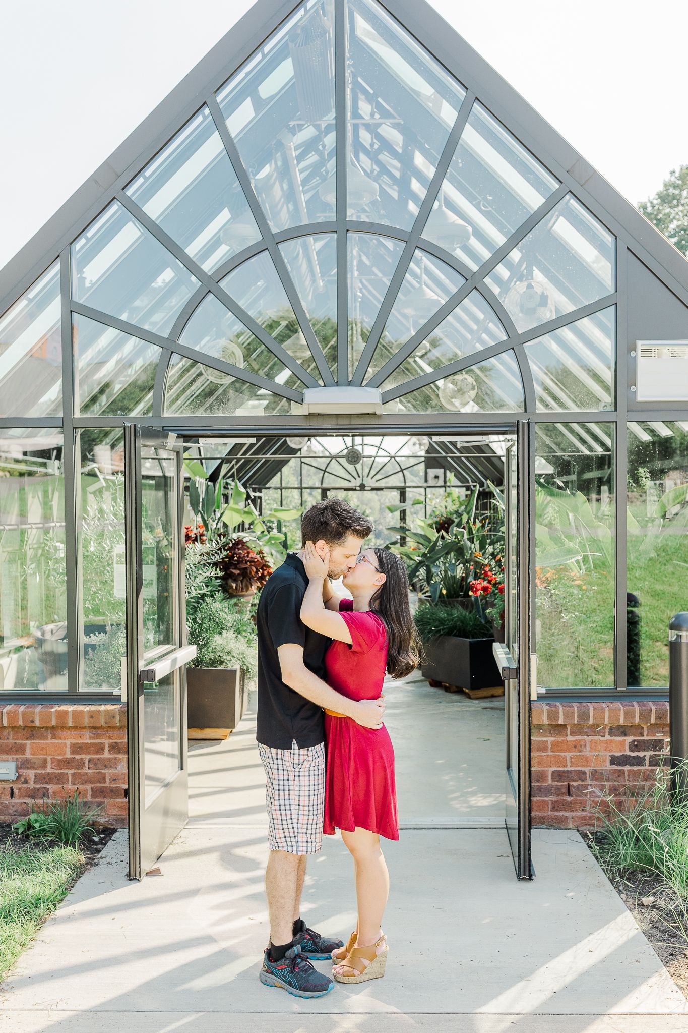 Romantic engagement photos in a glass greenhouse with architectural details.