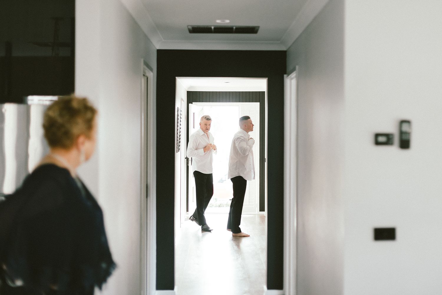 Silhouettes of people seen through doorway in bright white hallway.