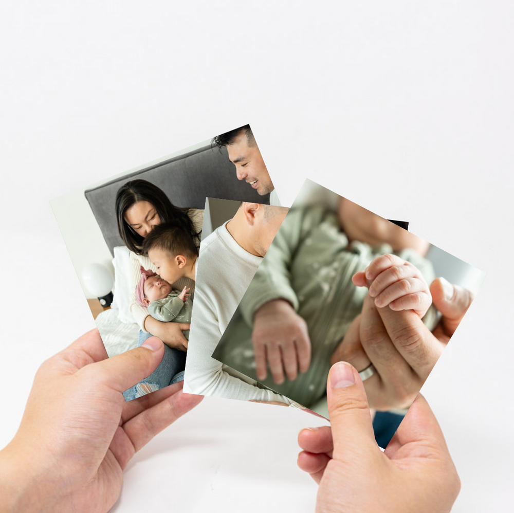 Hands showing a variety of different family photos printed out
