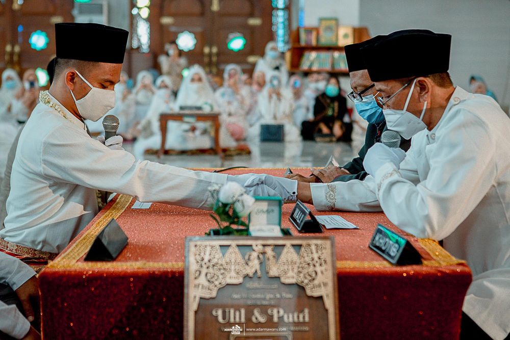 Two people in white dress and face masks sign documents on a red table.