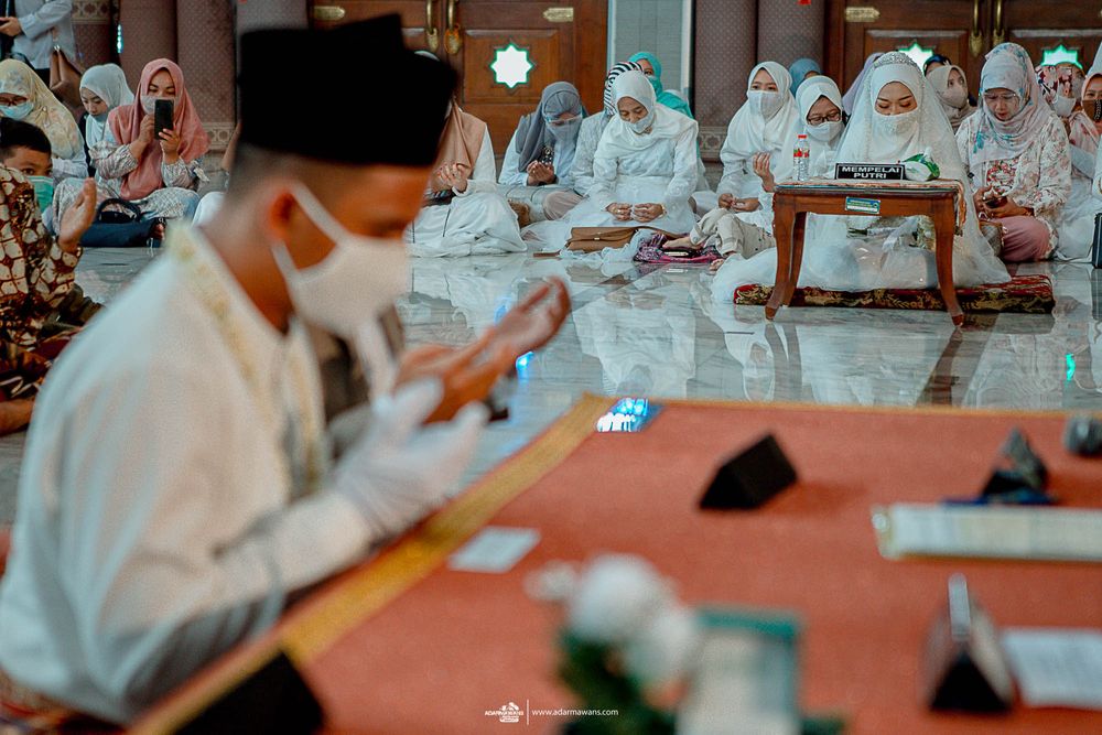A person in traditional Muslim attire signs documents during a ceremony.