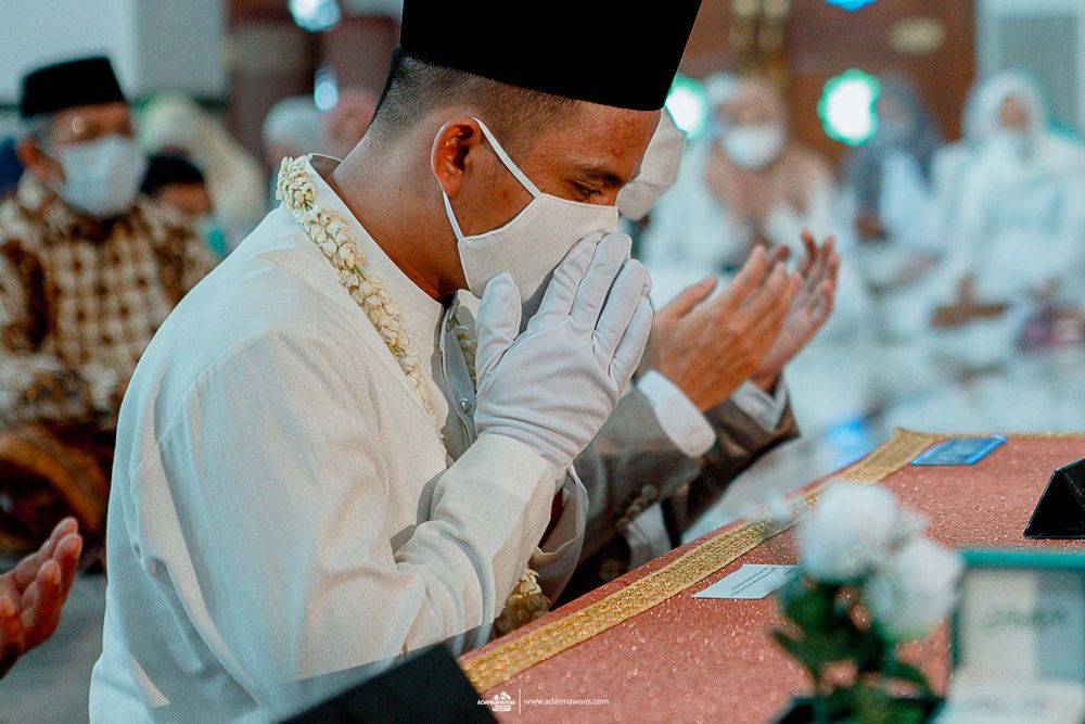 A person in traditional Islamic attire prays during a ceremony in a mosque.