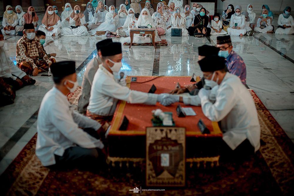 A traditional Islamic marriage ceremony takes place in a mosque with attendees watching.