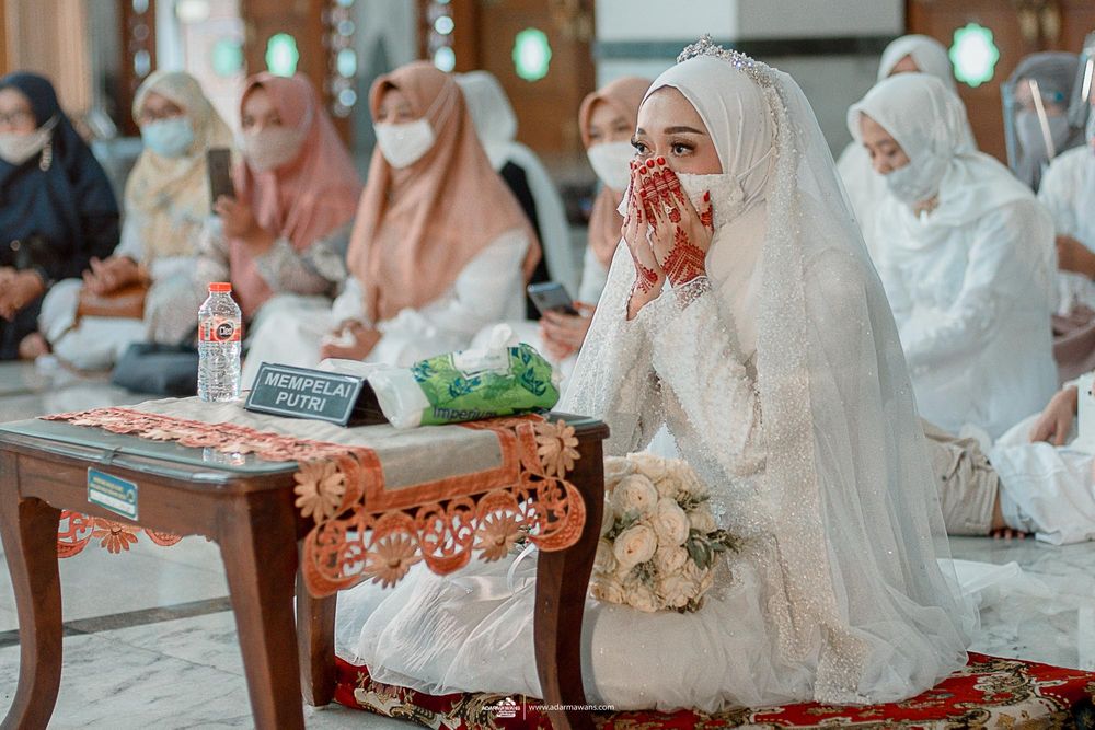 Group of women in white hijabs attending a religious ceremony at a mosque.