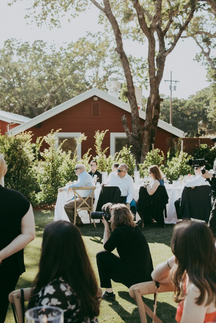 Outdoor garden wedding ceremony setup with red barn and trees in the background.