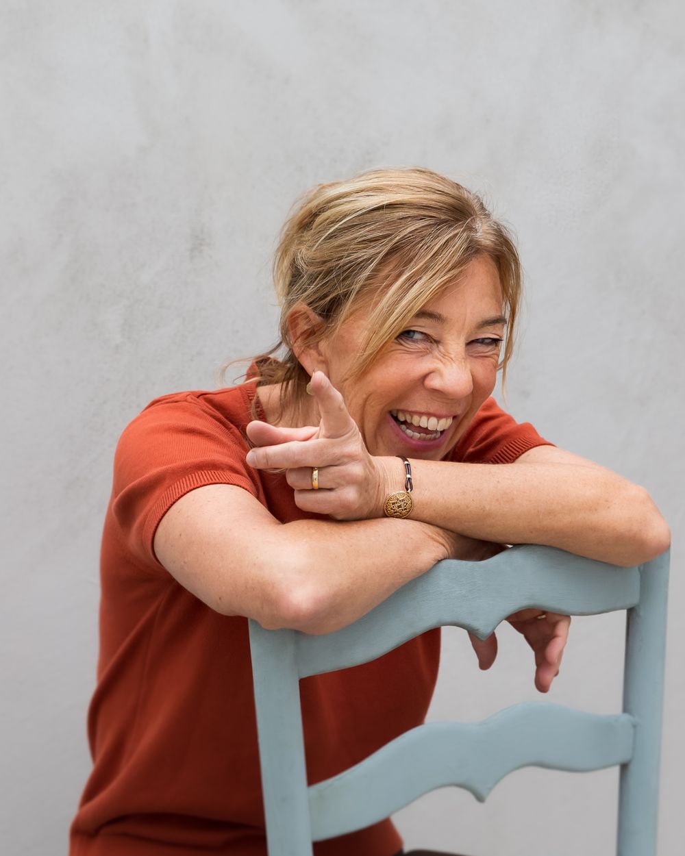 Speels personal branding portret van lachende vrouw op een stoel – zakelijke fotografie Arnhem