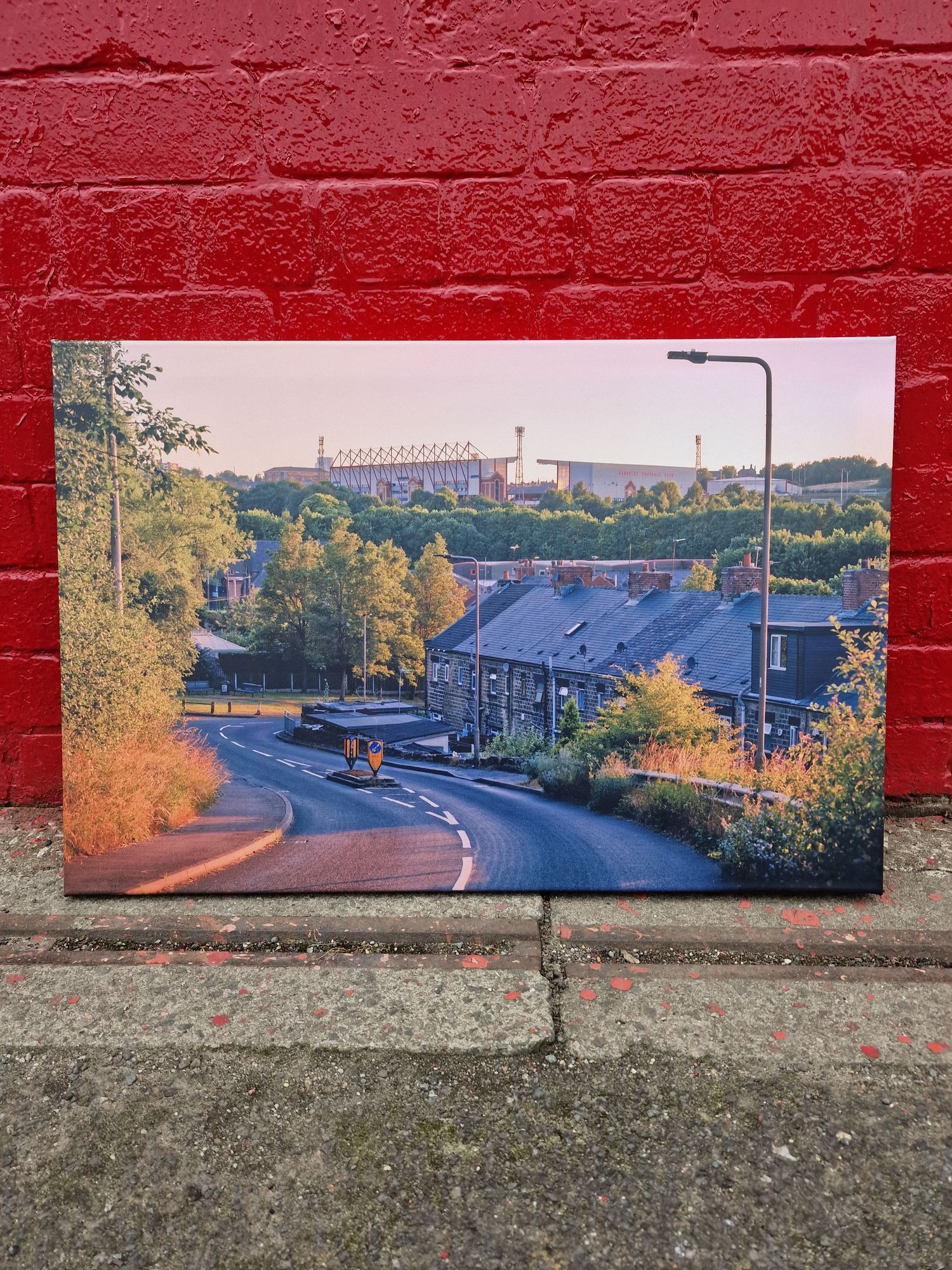 Red brick wall with painted landscape murals showing buildings, bridges and autumn trees.