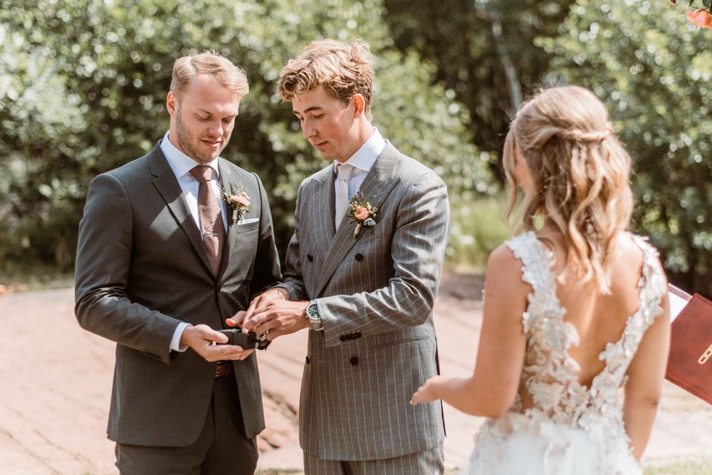 Wedding ceremony moment showing exchange of rings outdoors in natural lighting.