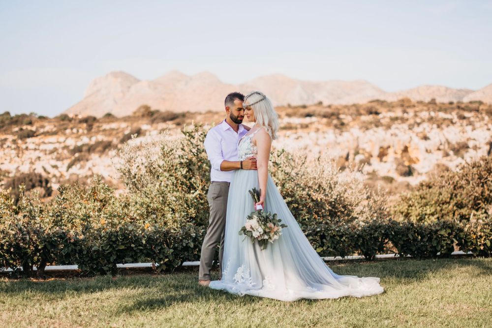 Wedding couple poses in desert landscape with mountains in background.