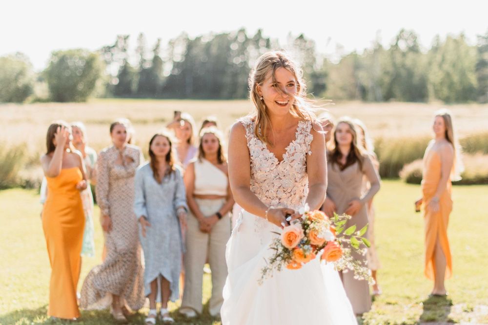 Wedding celebration with party members in colorful dresses standing in a sunny field.