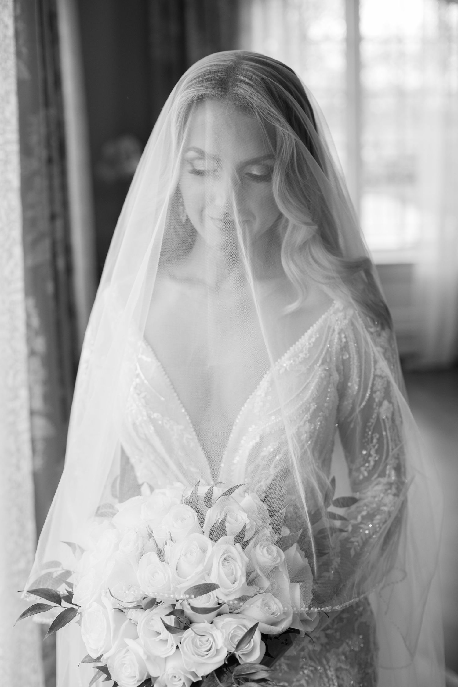 Soft black and white bridal portrait with veil and white rose bouquet.