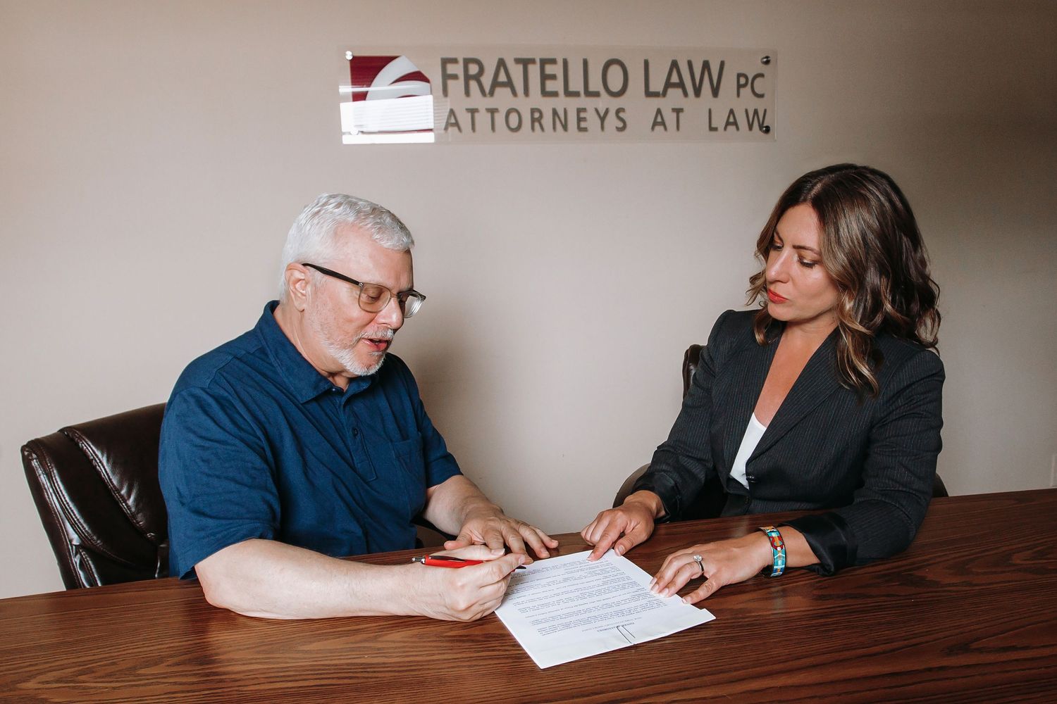 Attorney and client review legal documents at conference table in law office.