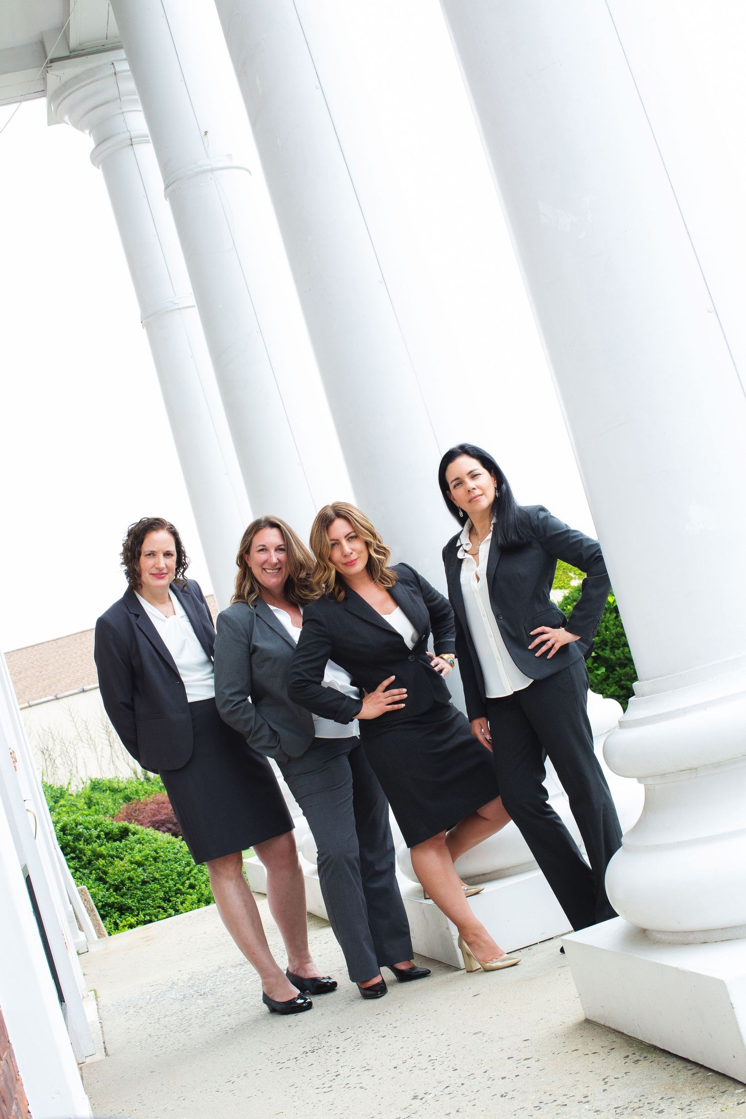 Group of legal professionals in business attire pose together by white classical columns.