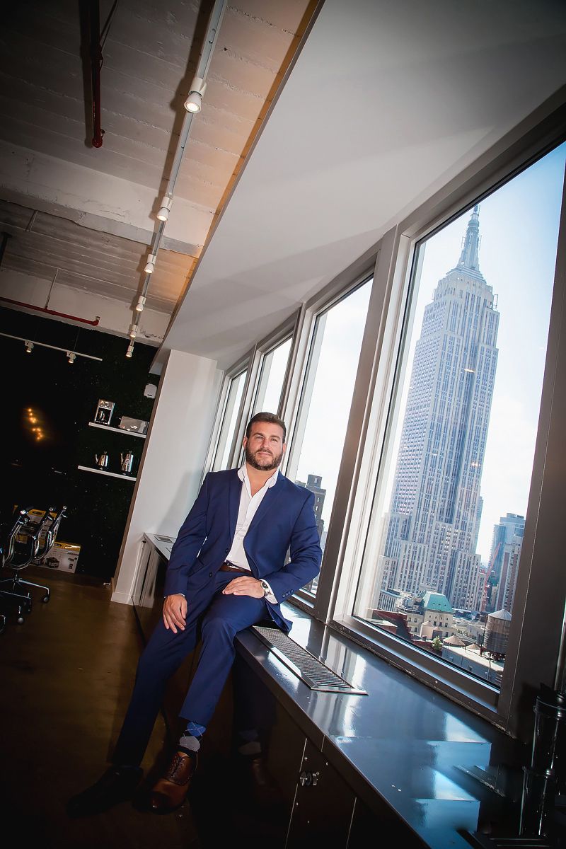 Business professional by window with Empire State Building view in modern office space.