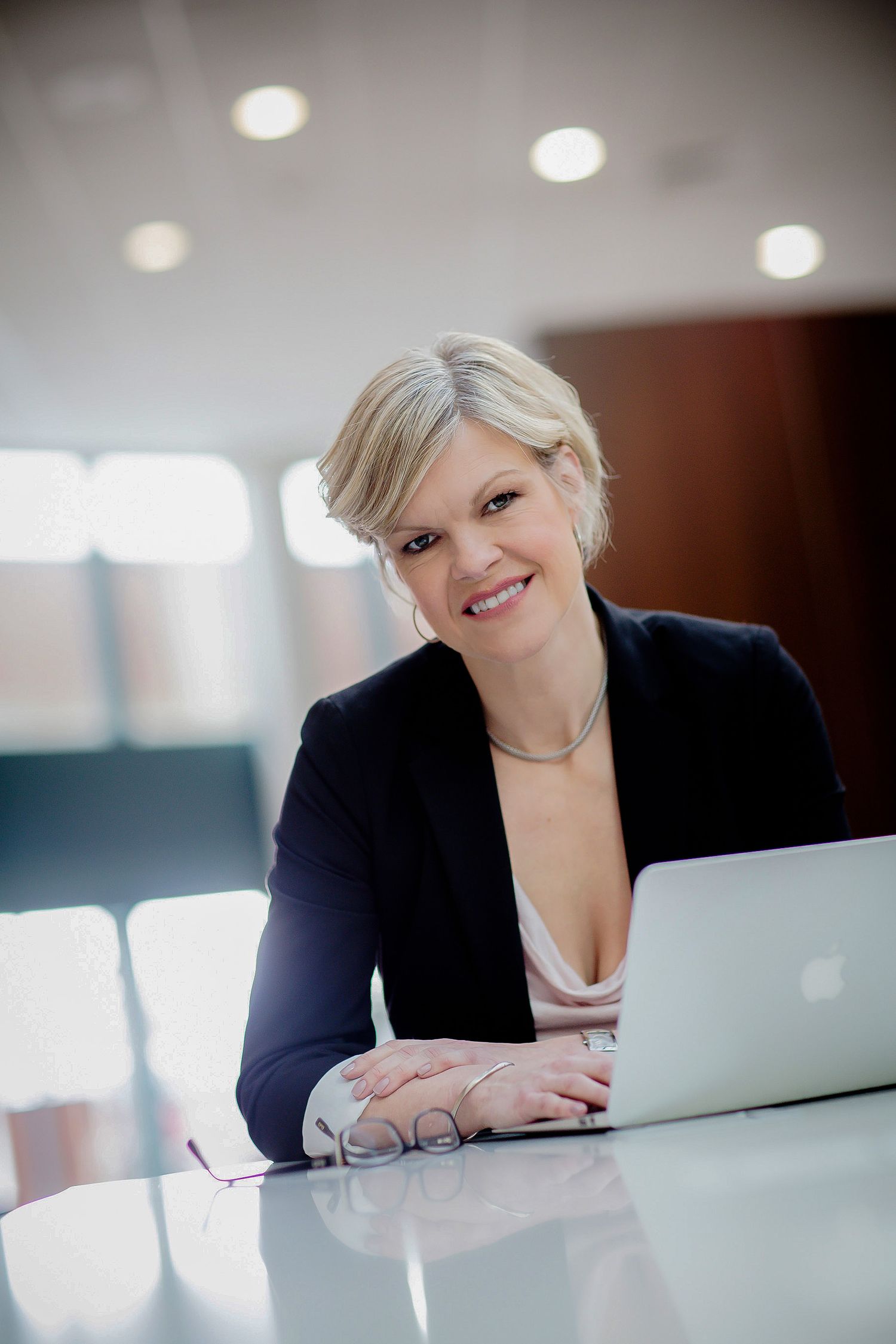 Professional business portrait at modern office desk with laptop computer.