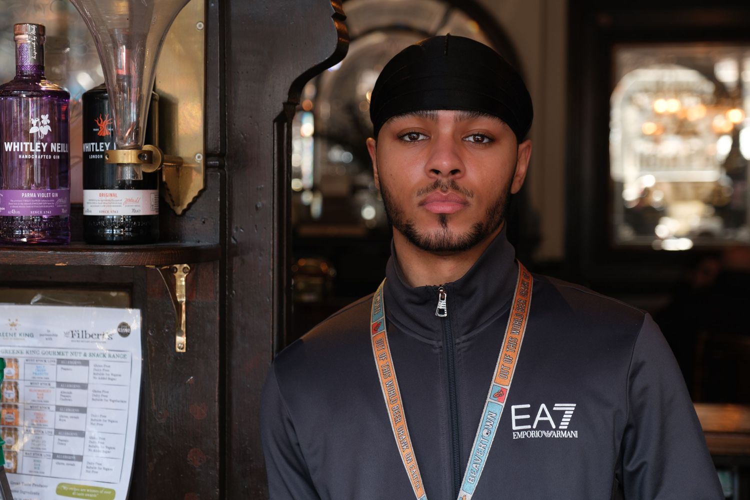 A young bartender in a pub in Islington stands in a doorway.