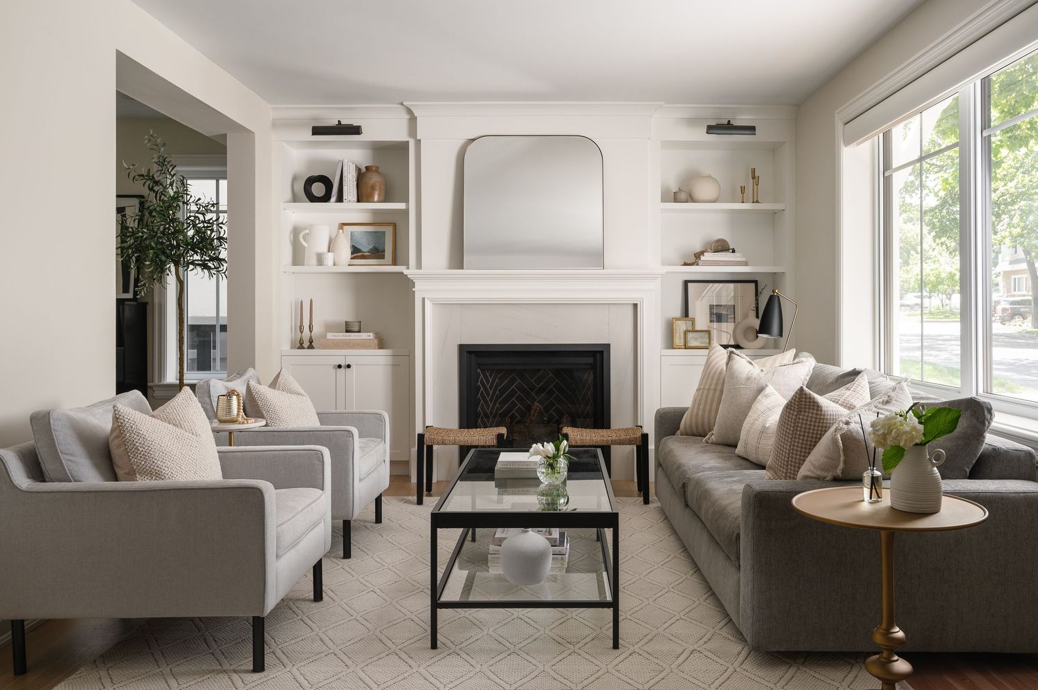 Symmetrical living room with built-in shelves, grey sofas, and arched fireplace.