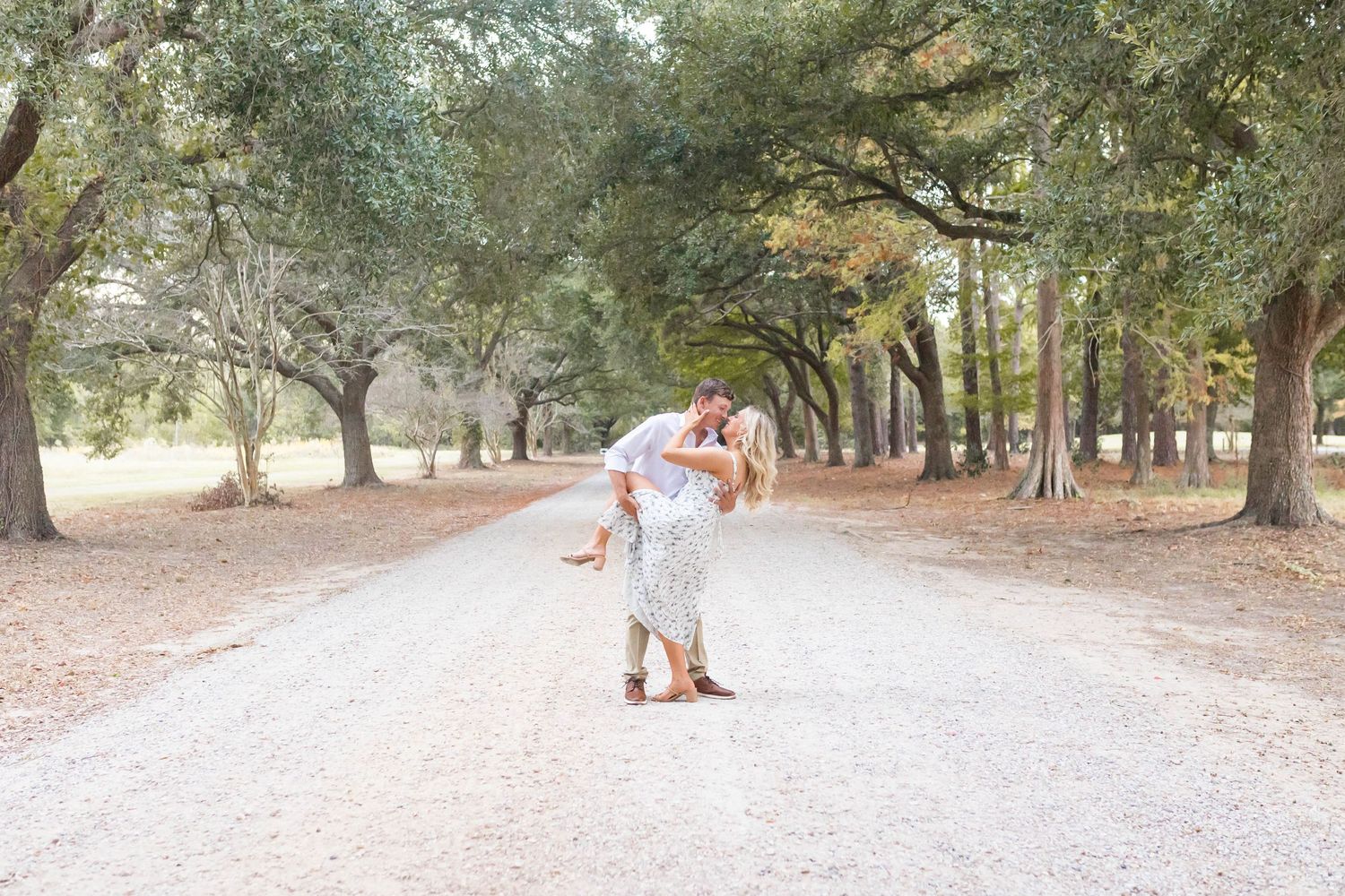 man and woman dip and kiss among tree arch