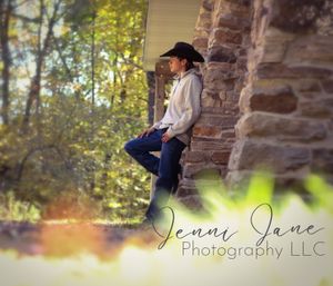 Rustic outdoor portrait session against a stone wall surrounded by autumn foliage.