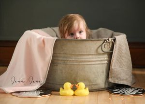 Playful bath time photo setup with rubber ducks and a vintage metal tub.