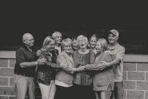 A group poses together against a brick wall in a black and white photo.