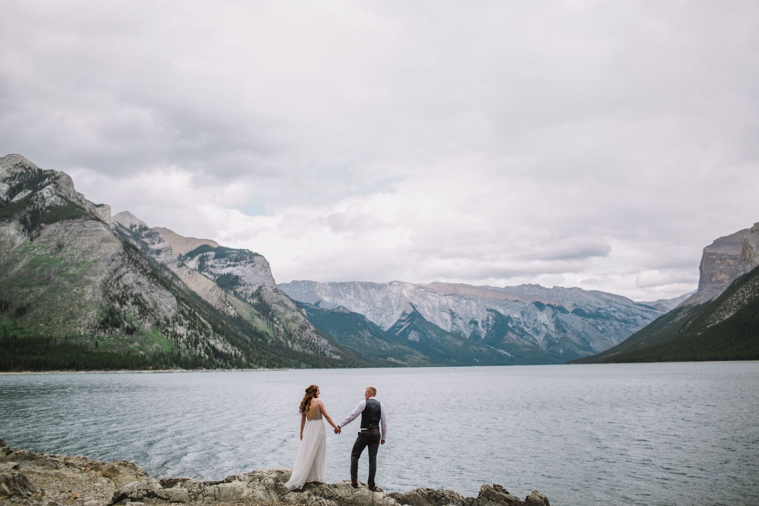 A couple on their wedding day  stand amidst windswept mountains in Banff Alberta