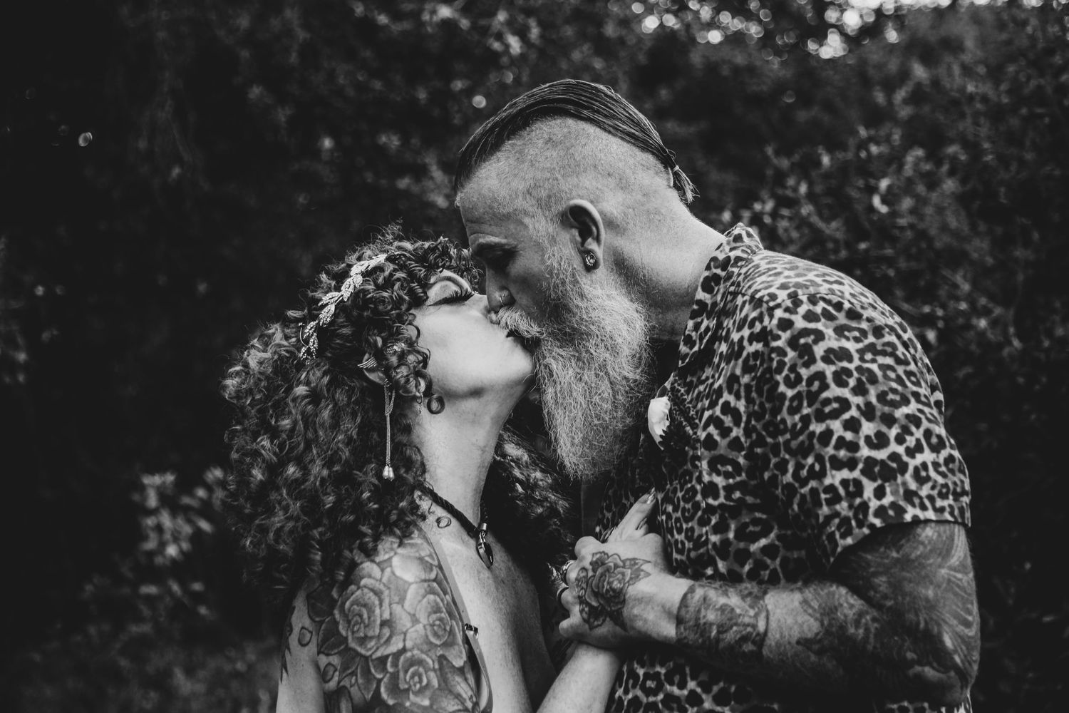 A black and white portrait of a couple sharing an intimate moment outdoors.