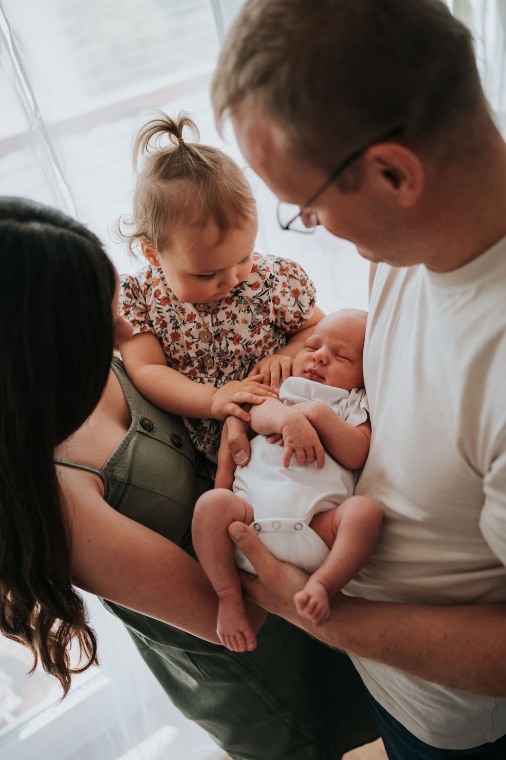 noworodek, siostra, mama i tata przy oknie - sesja domowa Kraków