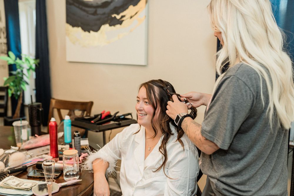 Professional makeup artist applies cosmetics on clients in preparation for special occasion in sunlit room.