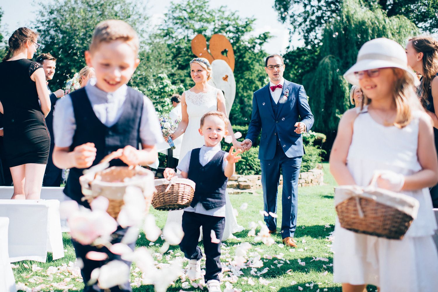 Festive outdoor celebration with flower petals being tossed in a garden setting.