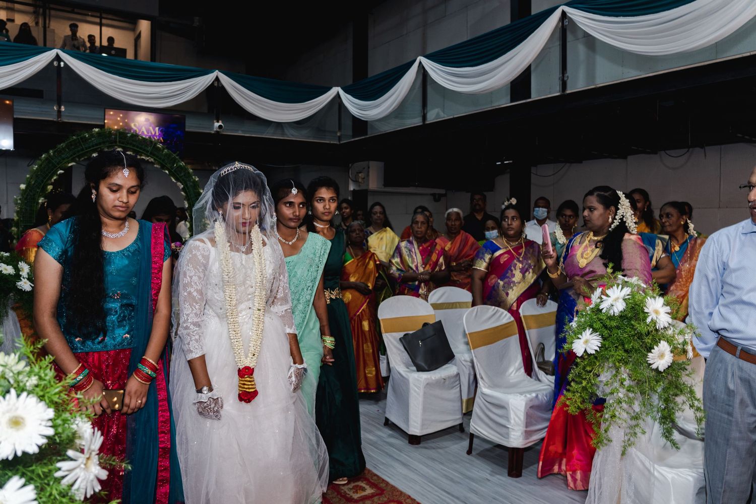 Wedding guests gather under draped white canopy decorations during ceremony.