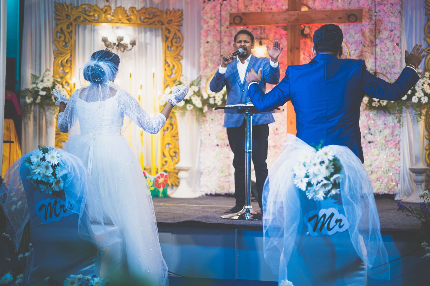A couple dances during their wedding reception with golden decor and floral arrangements.