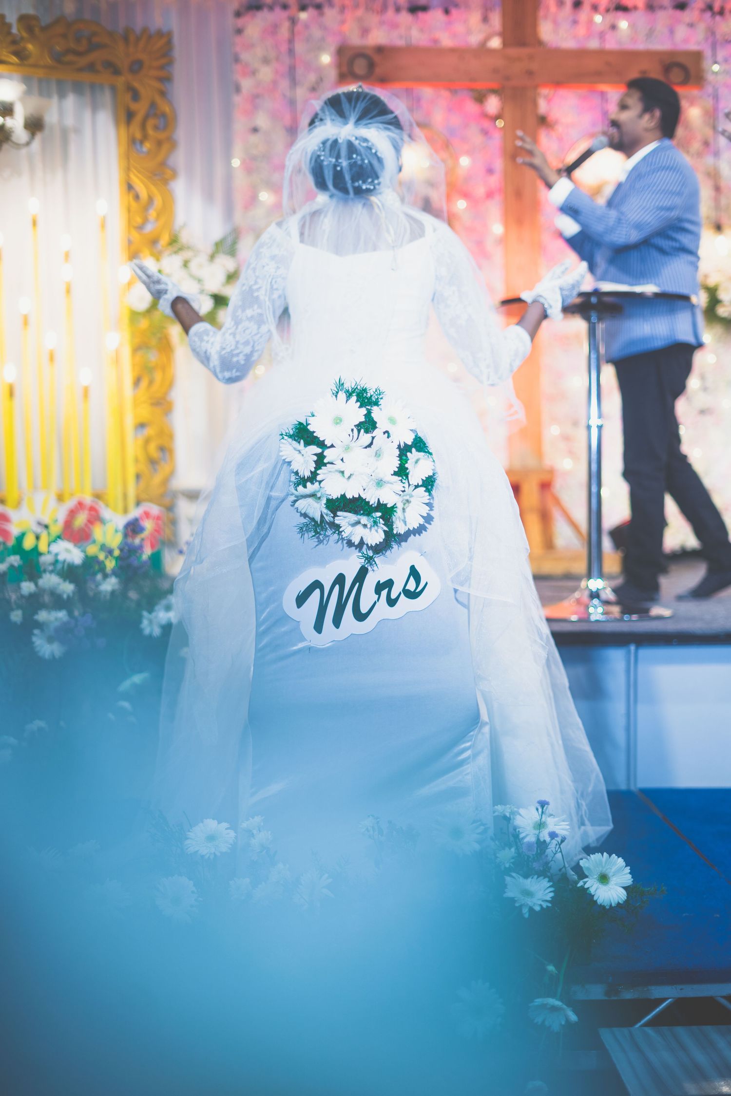 A bride in white dress with 'Mrs' decoration dances on stage during wedding reception.