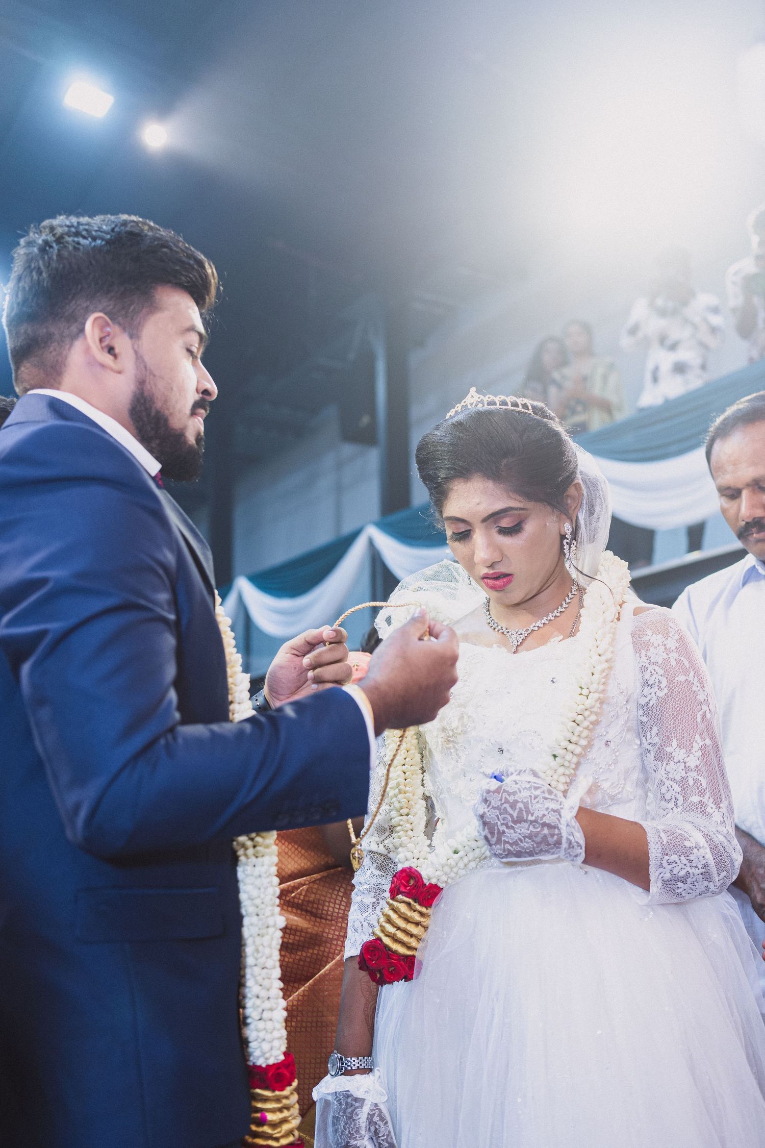 Wedding ring exchange ceremony with bride in white dress and groom in navy suit.