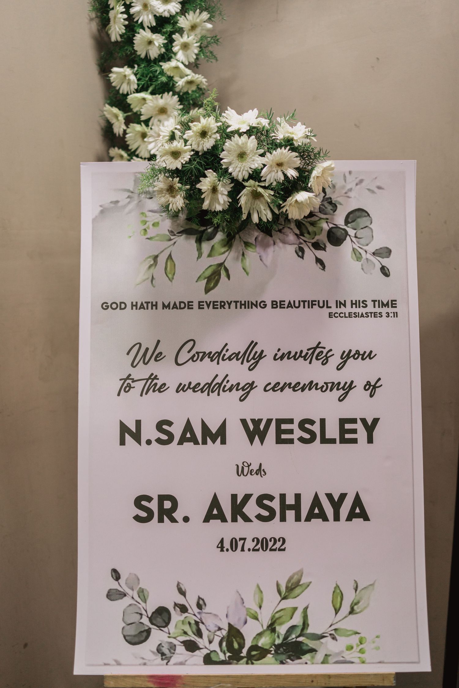 Wedding invitation with white floral decor featuring quote from Ecclesiastes.