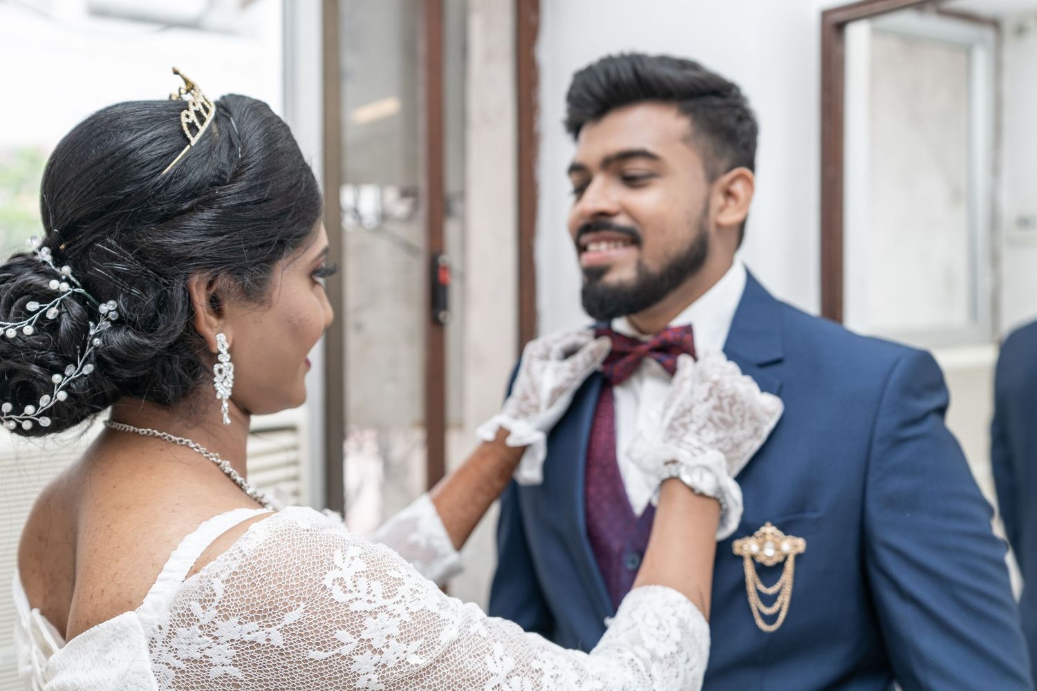 A touching moment between newlyweds as they adjust formal attire.
