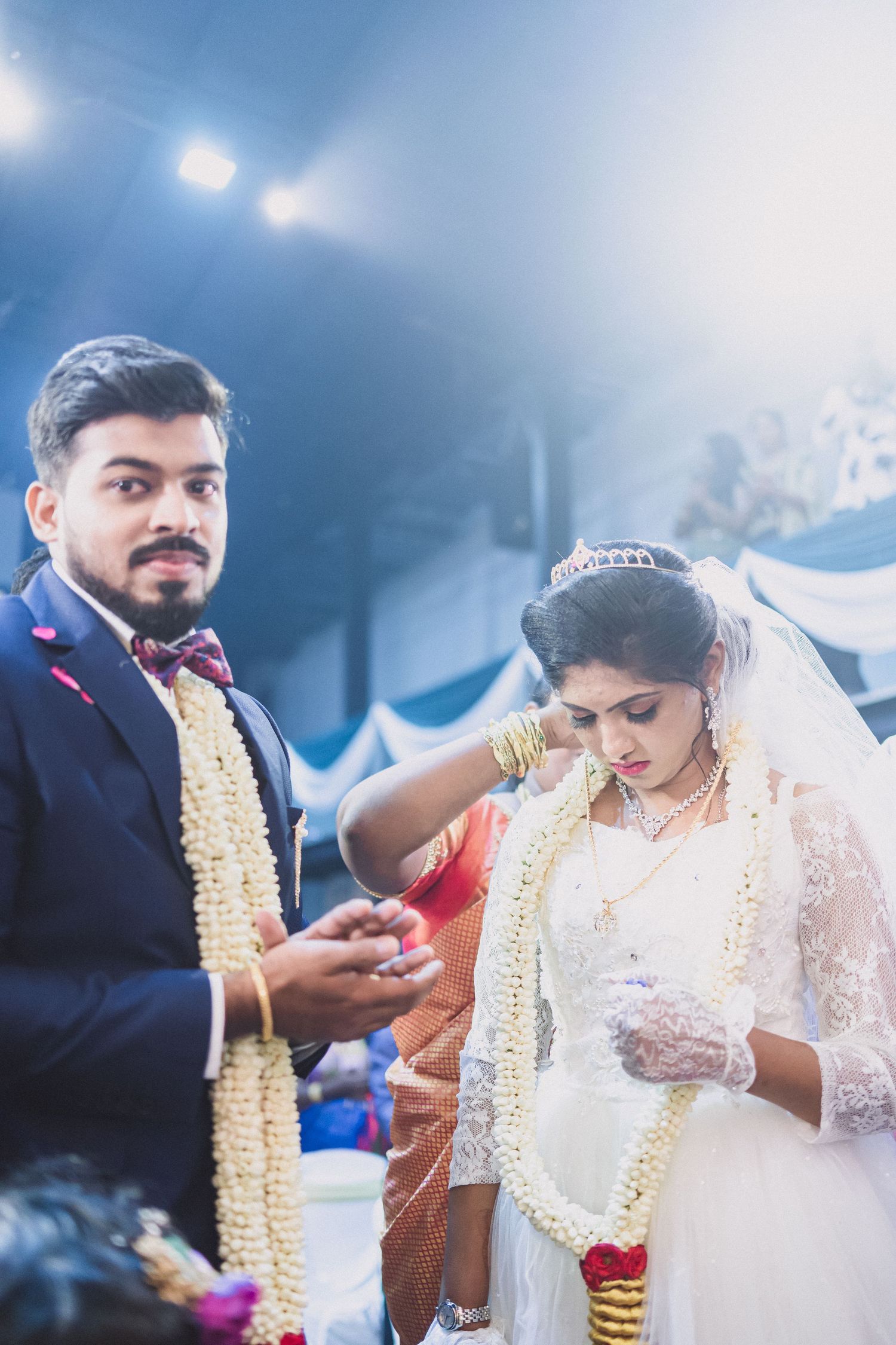 Traditional Indian wedding ceremony with couple wearing garlands during ring exchange.