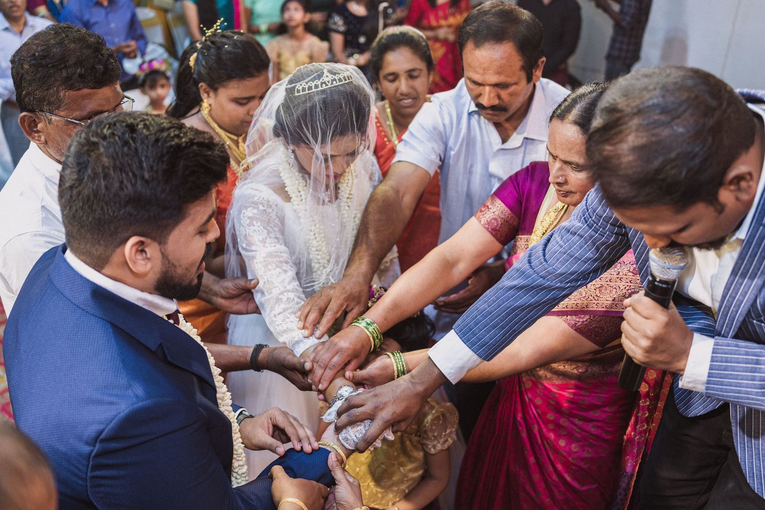 Group participating in traditional wedding ceremony ritual with hands joined together.