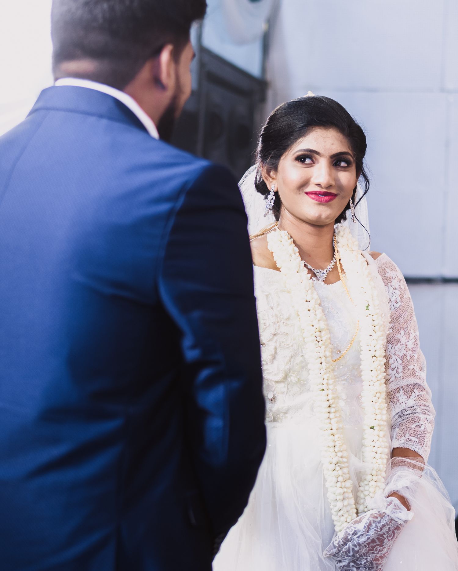 Candid moment between couple during Christian wedding ceremony with bride in white lace dress.