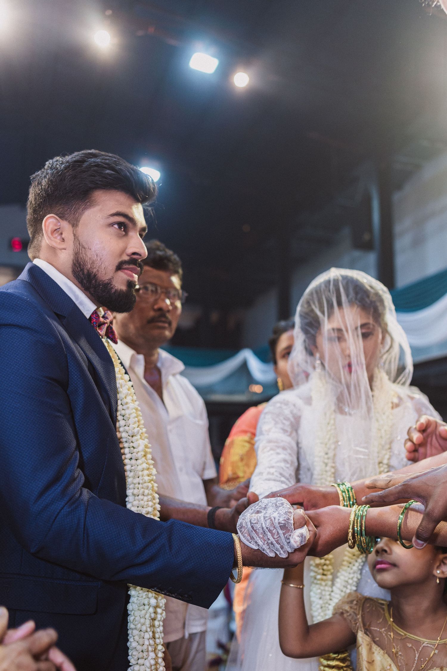 Formal ceremony participants engaging in traditional ritual under dramatic stage lighting.