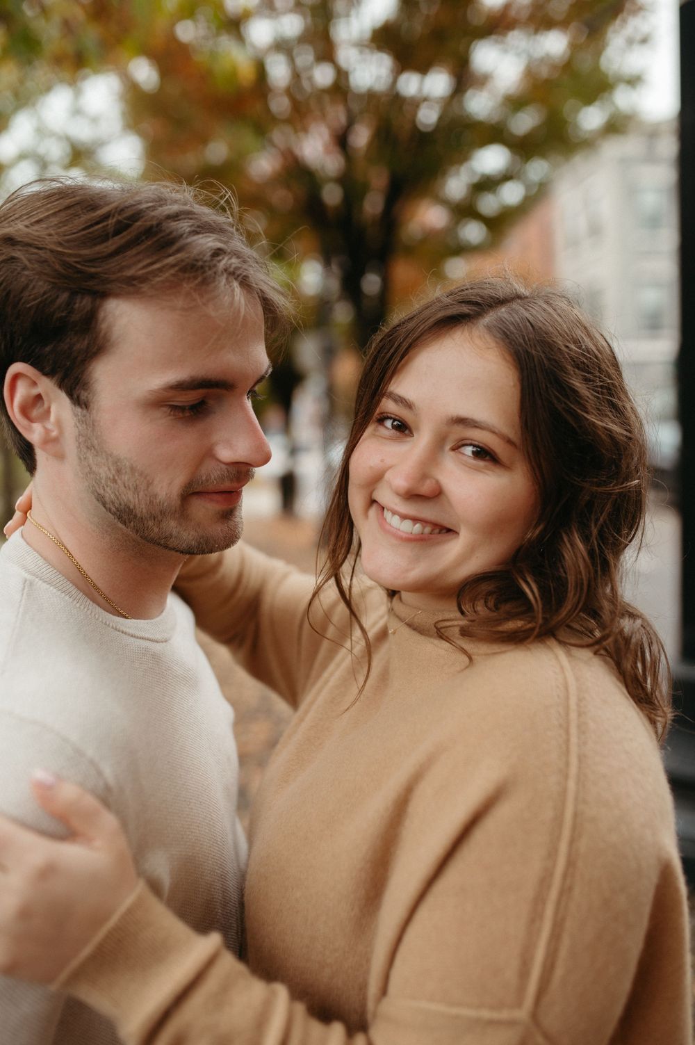Couple in coordinating sweaters share a tender moment on an autumn day.