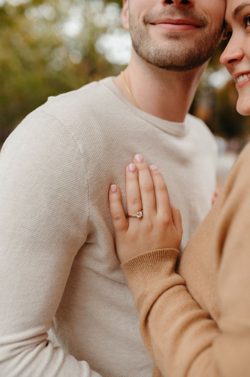 Close-up of engagement ring and hands against cream sweater during autumn photoshoot.