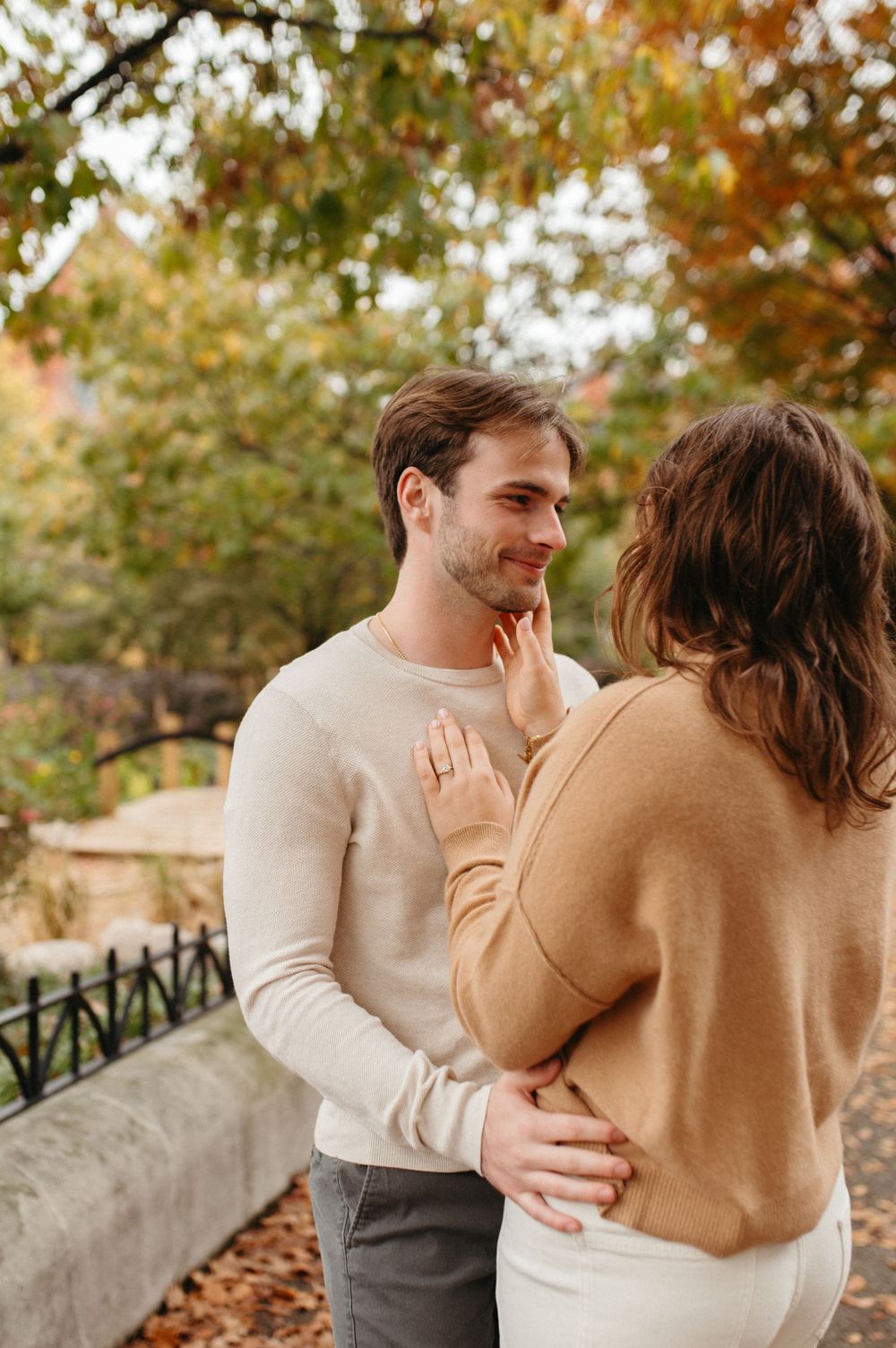 A tender moment between a couple against an autumn backdrop with fallen leaves.
