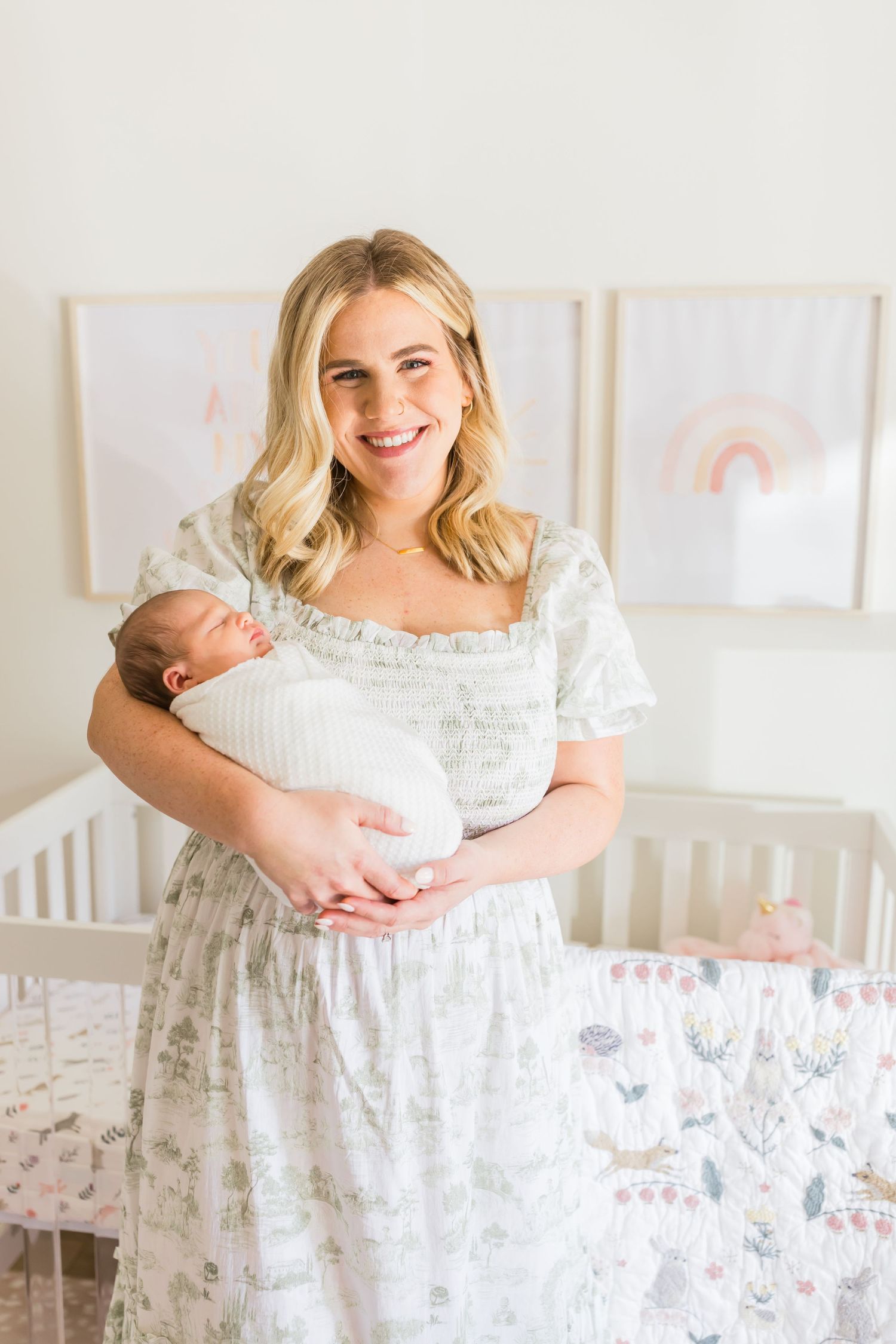 A bright nursery setting with white crib and pastel rainbow wall art.